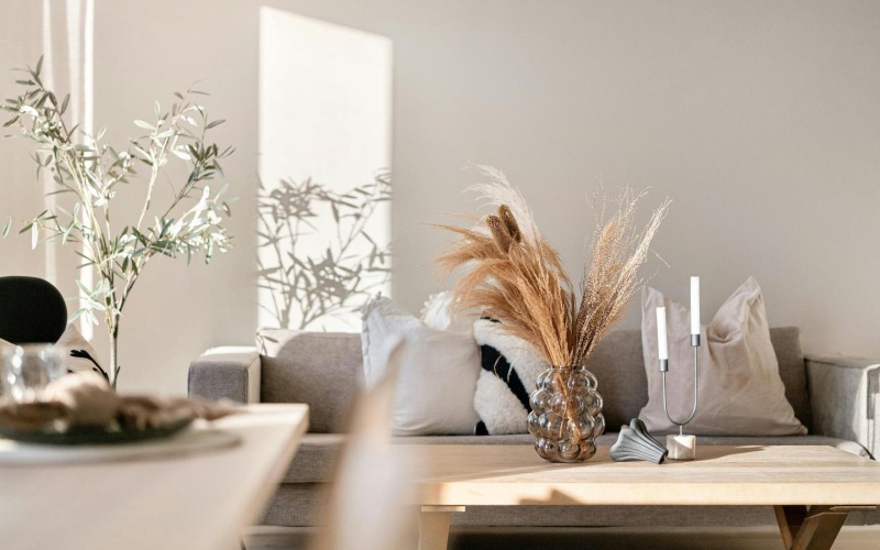 a living room with a couch and a table with a vase with flowers